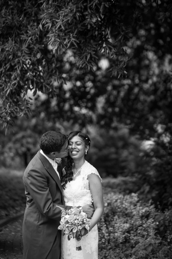 groom kissing bride in black and white